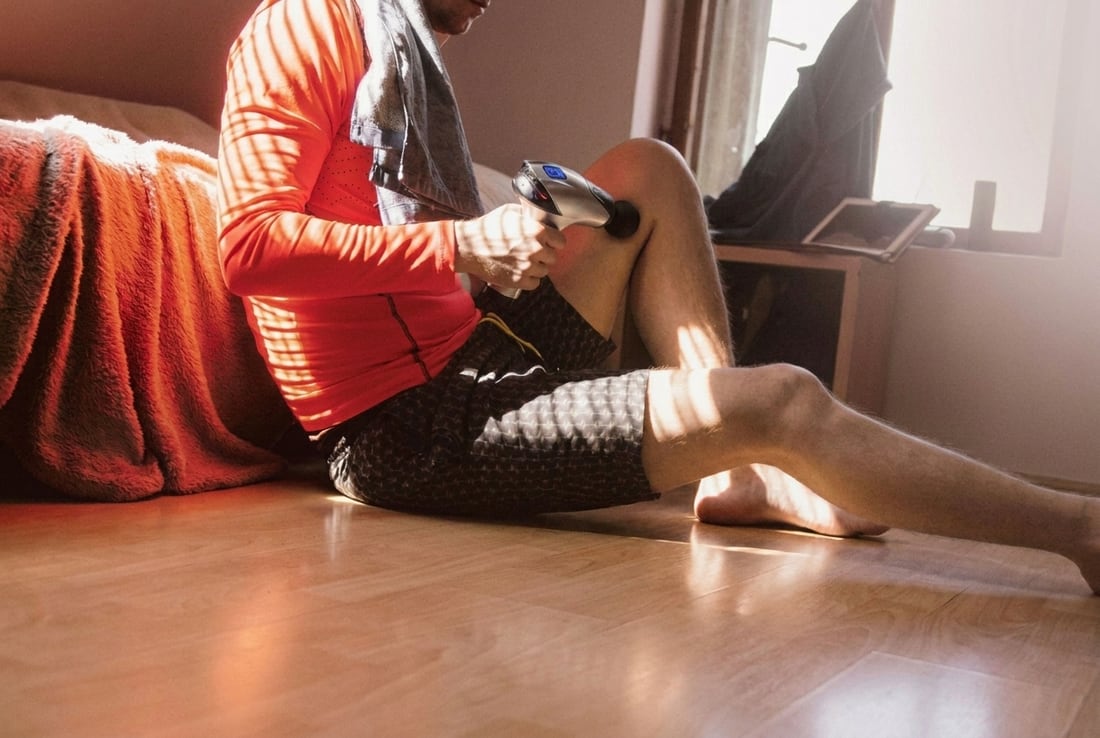 Person sitting on the floor at home using the EVURON ARC Pro above the knee in afternoon light.