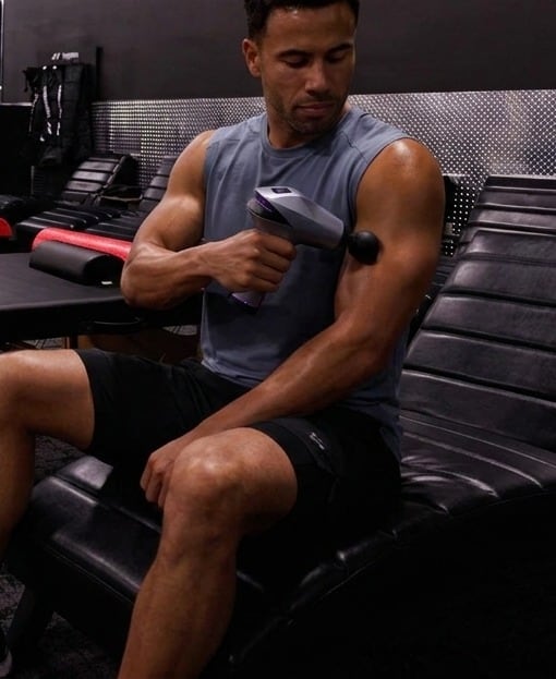 Athlete seated in a recovery area using the EVURON ARC Pro on the upper arm.
