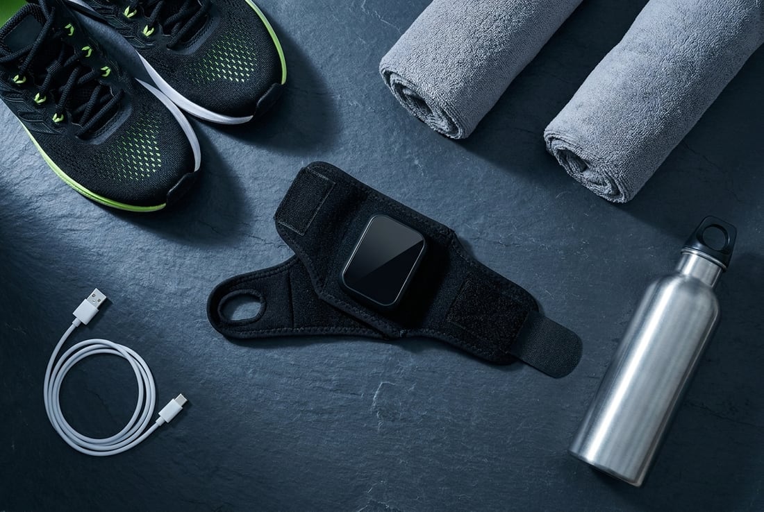 The EVURON EMBER Max laid out on slate beside its USB charging cable, a water bottle and folded towels.
