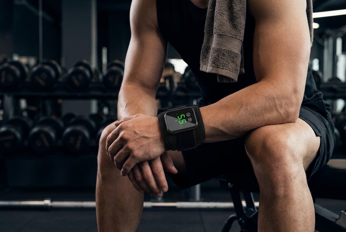 Athlete seated between sets with the EVURON EMBER Max fitted around the wrist.